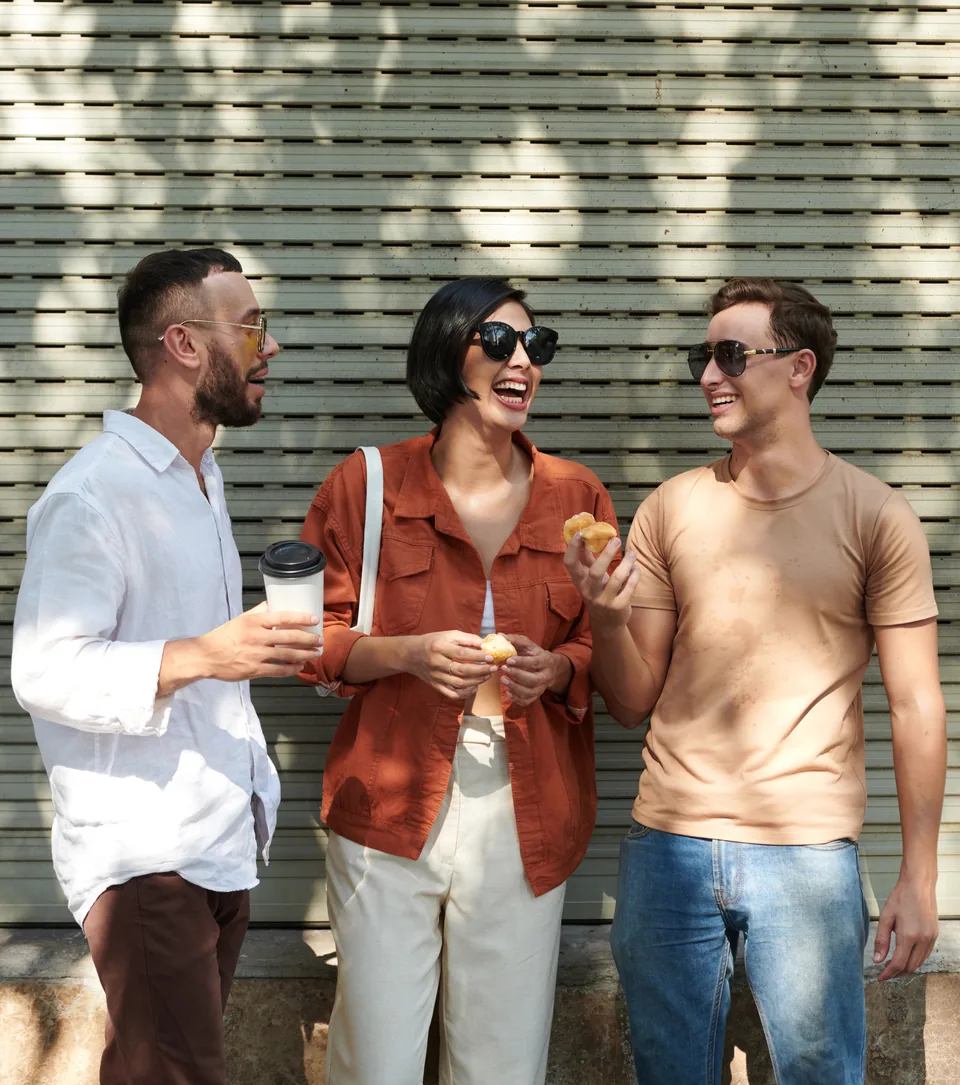 Three people talking and smiling outside a house