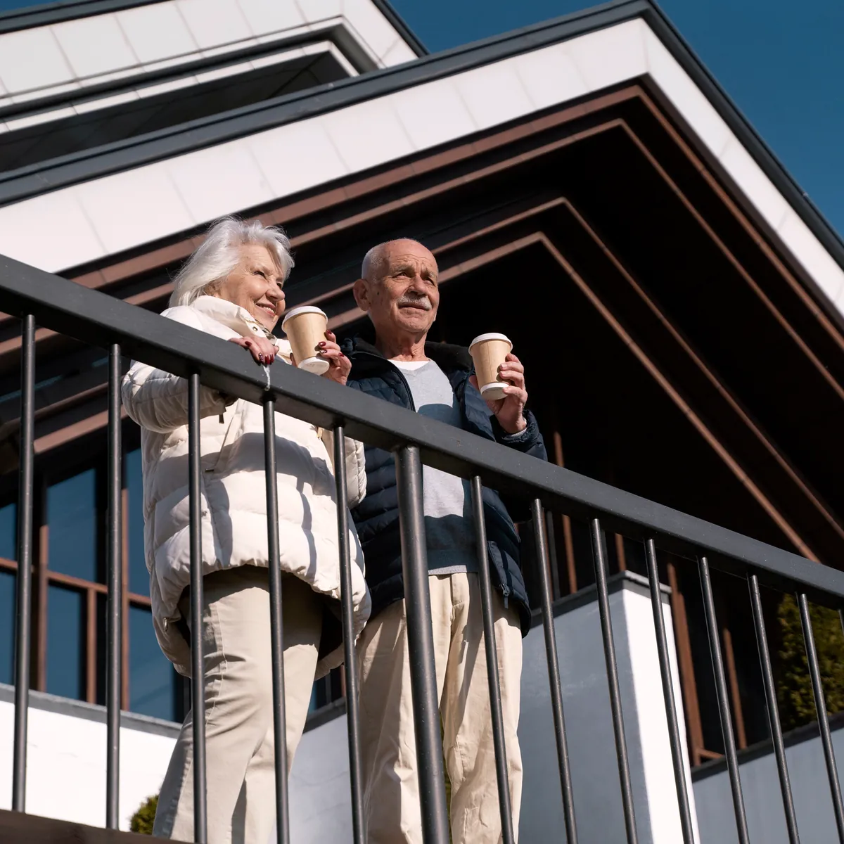 Older couple with coffee on the balcony of their home